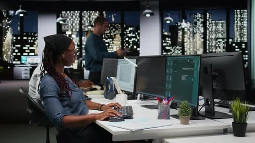 Woman Typing at Computer in Modern Office at Night