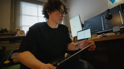 Man with Glasses Coding Software on Multiple Laptops