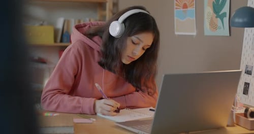 Teenage Student Learning in Online School Writing and Listening to Teacher with Laptop and