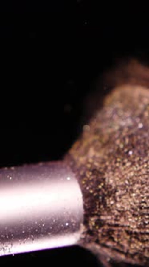 Vertical Screen Makeup Brushes Touch Each Other on Dark Background and Small Particles of Cosmetics