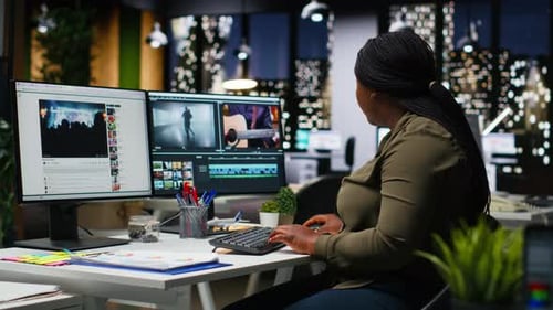 Woman Working at Computer with Dual Screens at Night