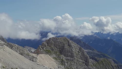 A Wide Panoramic Shot of a Limestone Peak High in the Alps with Clouds Floating in the Background