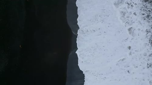 Waves Crashing on Black Sand Beach from Above