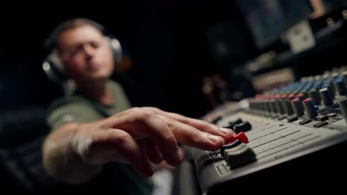 A close-up of a mixing console device used by a man working as professional sound engineer