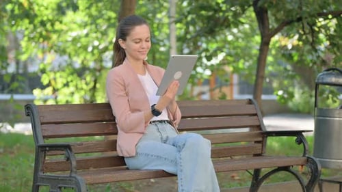 Young Woman Using Digital Tablet while Sitting in Park