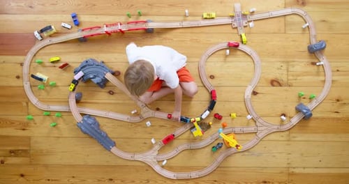 Child Playing with Toy Train on Wooden Floor