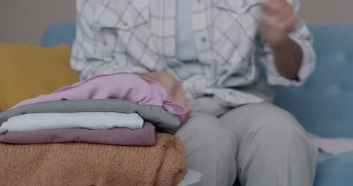 Closeup of Female Hands Sorting and Folding Clothes Busy with Laundry and Housework in Apartment