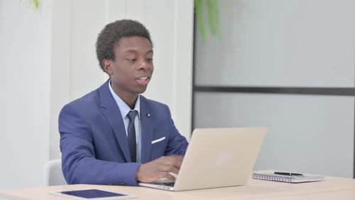 Young Adult in Suit Video Conferencing at Desk