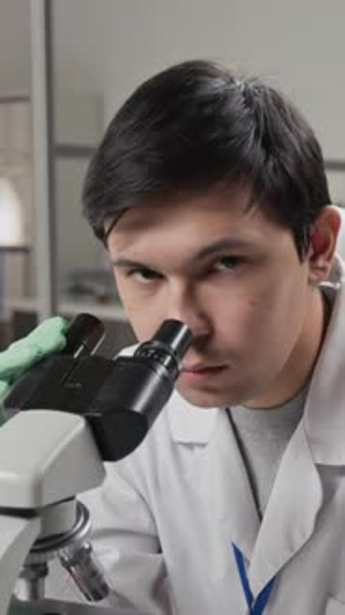 Young Man Using Microscope in Laboratory Setting