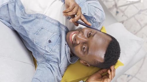 Young Man Chatting on Phone While Lying Down