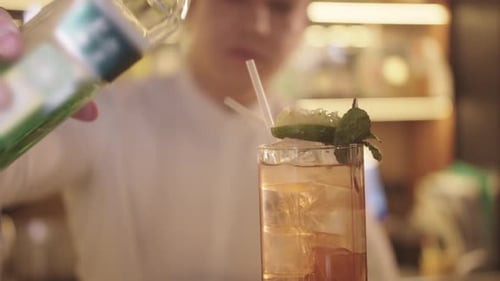 Bartender Preparing Alcohol Cocktails in Bar Adds Green Alcohol in Glass