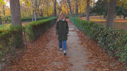 Taking a Leisurely Autumn Stroll in the Park a Woman Enjoys Walking Along the Leafy Path