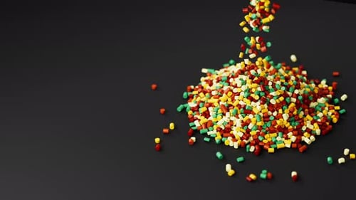 Buntes Kunststoff-Polypropylen-Granulat, das aus einem Becher auf einen Stapel Granulat gegossen wird Masterbatch-Polymer