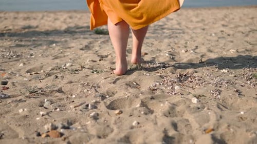 Legs of Happy Woman Running Barefoot Along Sandy Beach Towards Sea Closeup