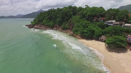 Dolly Aerial shot of tourist beach in tropical Koh Chang with small resorts and Jungle sea view