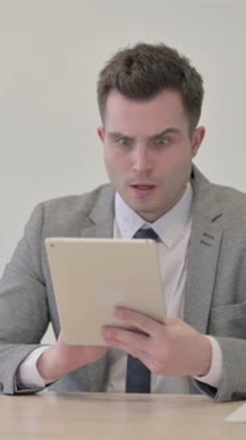 Man in Suit Uses Tablet with Surprised Expression