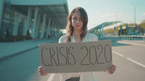 Crisis 2020 Belle femme sérieuse caucasienne montrant une bannière invocatoire debout près d'un aéroport