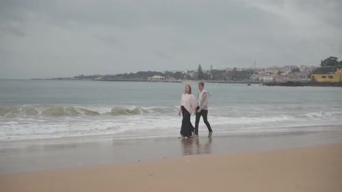 Romantic Couple Walking on Beach on Cloudy Day