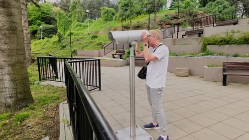 Woman looks through observation telescope at scenic lookout point