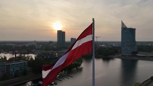 Aerial View of Latvian Flag Waving on Flagpole in Capital City Riga at Sunset Daugava River Slow