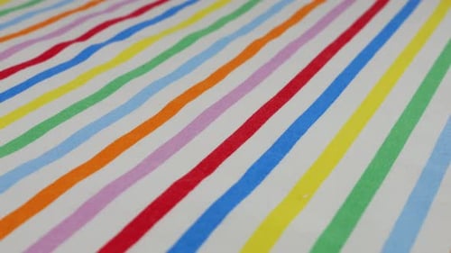 Top view of white cotton fabric with rainbow stripes rotated on the display case. Textile background