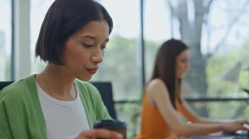 Two Women Working Computers Panoramic Window Office Closeup Lady Sipping Coffee