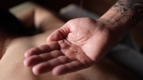 Der Massagetherapeut gießt Massageöl auf die Hand