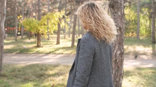 Portrait of Young Attractive Curly Woman Walking in the Autumn Park on a Sunny Day