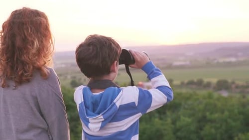 Child with Binoculars and Adult Look at Sunset
