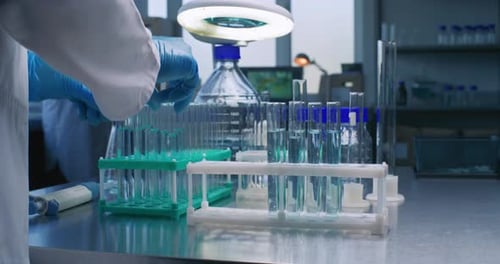 Close Up of Scientist Putting Test Tubes with Blue Liquid in Rack
