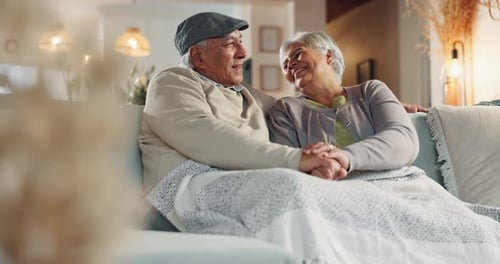 Old couple, kiss and funny conversation in home, support and blanket for comfort in lounge