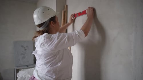 A Skilled Female Builder Meticulously Inspecting an Interior Space While Wearing Safety Gear