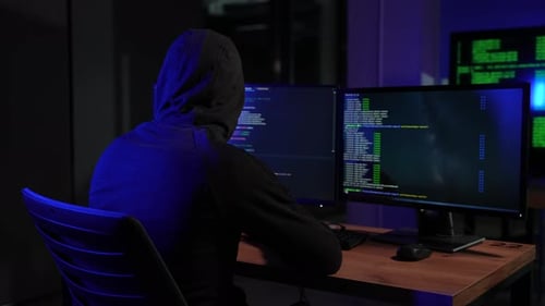 Hooded Hacker Coding at Computer Desk at Night