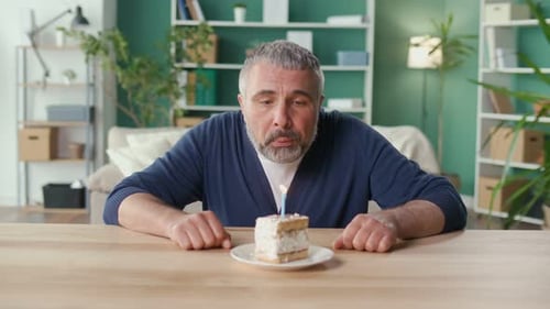 Middle Aged Man Blowing Out Birthday Candle