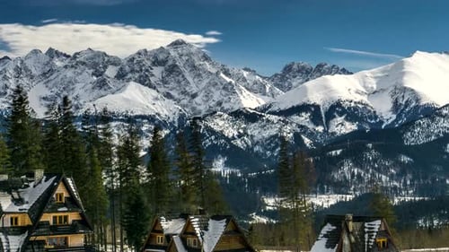 Snowy Mountains Behind Cabins in a Winter Landscape