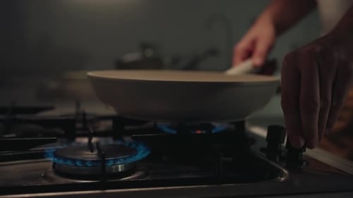 Man Placing Pot Onto Gas Stove Turning on Gas for Heating Up Sunflower Oil in Skillet and Warming