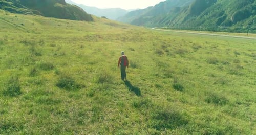 Flight Over Backpack Hiking Tourist Walking Across Green Mountain Field