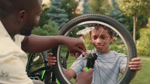 Father and Son Repairing Bicycle Tire Outdoors