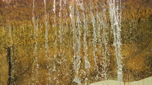 Artificial waterfall against the backdrop of a stone wall on the hotel grounds.