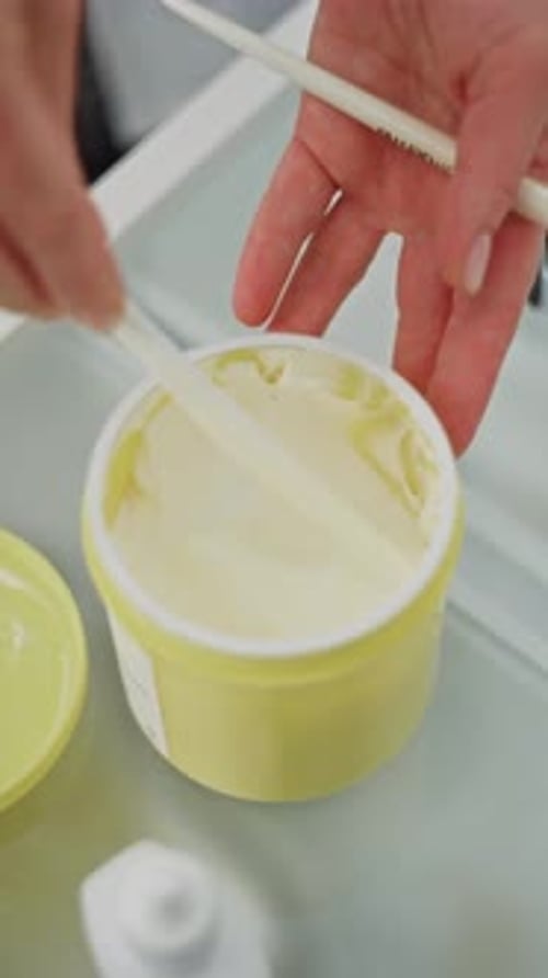 Hands Scooping Beauty Cream From a Yellow Jar