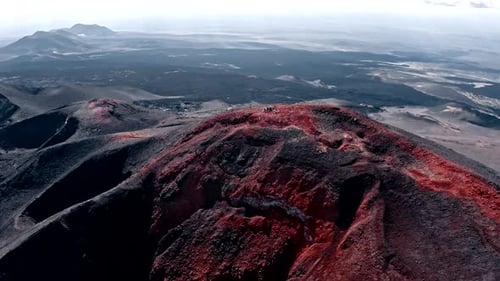 People Standing On Top Of A Mountain Overlooking A Volcanic Area Aerial