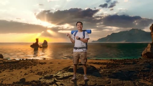 Full Body Of Asian Male Hiker Smiling And Pointing To Side on Beach