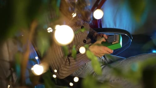 Woman Playing Kalimba at Home Surrounded By Christmas Lights
