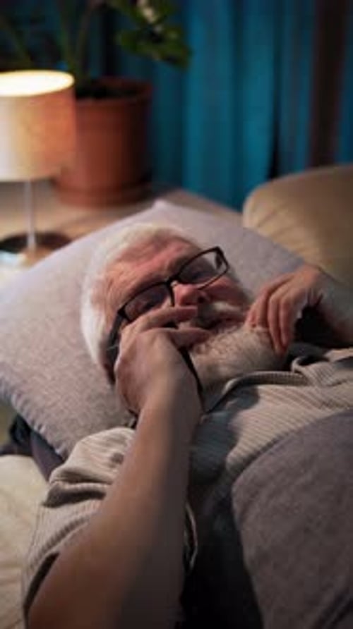 At Night Man Lying in Bed He Touches His Beard and Talk to Someone on Phone