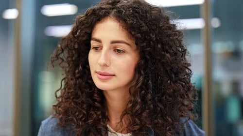 Confident Businesswoman with Curly Hair Smiles in Modern Office
