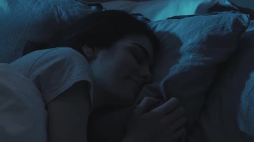 Woman Sleeping Peacefully in Dark Bedroom at Night