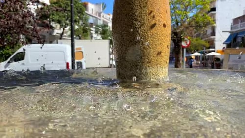 Drops of water fall in water fountain in a typical Spanish street in Marbella old town, city life on