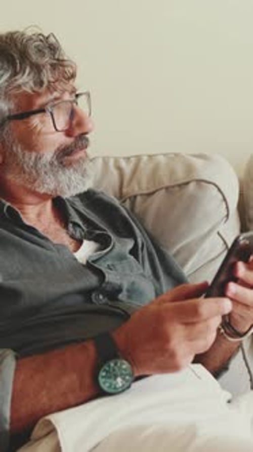 Man Relaxing on Couch Using Smartphone