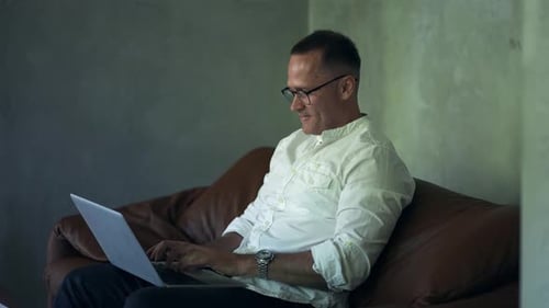 Smiling Businessman Working on Laptop Computer at Home Office