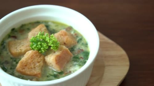spinach soup with bread in white bowl